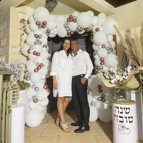 זוג מול קשת בלונים לבנה בכניסה לאירוע