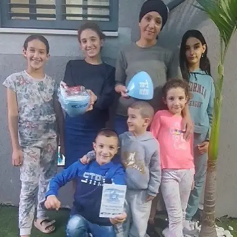 משפחה עם ילדים מחזיקה מארז מתנה ובלון