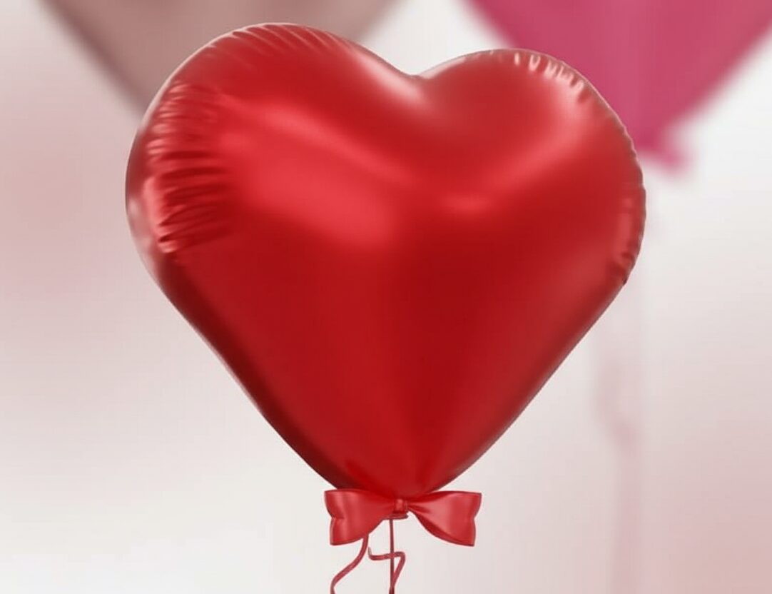 בלון לב אדום מבריק עם סרט קשור, רקע ורוד עדין
